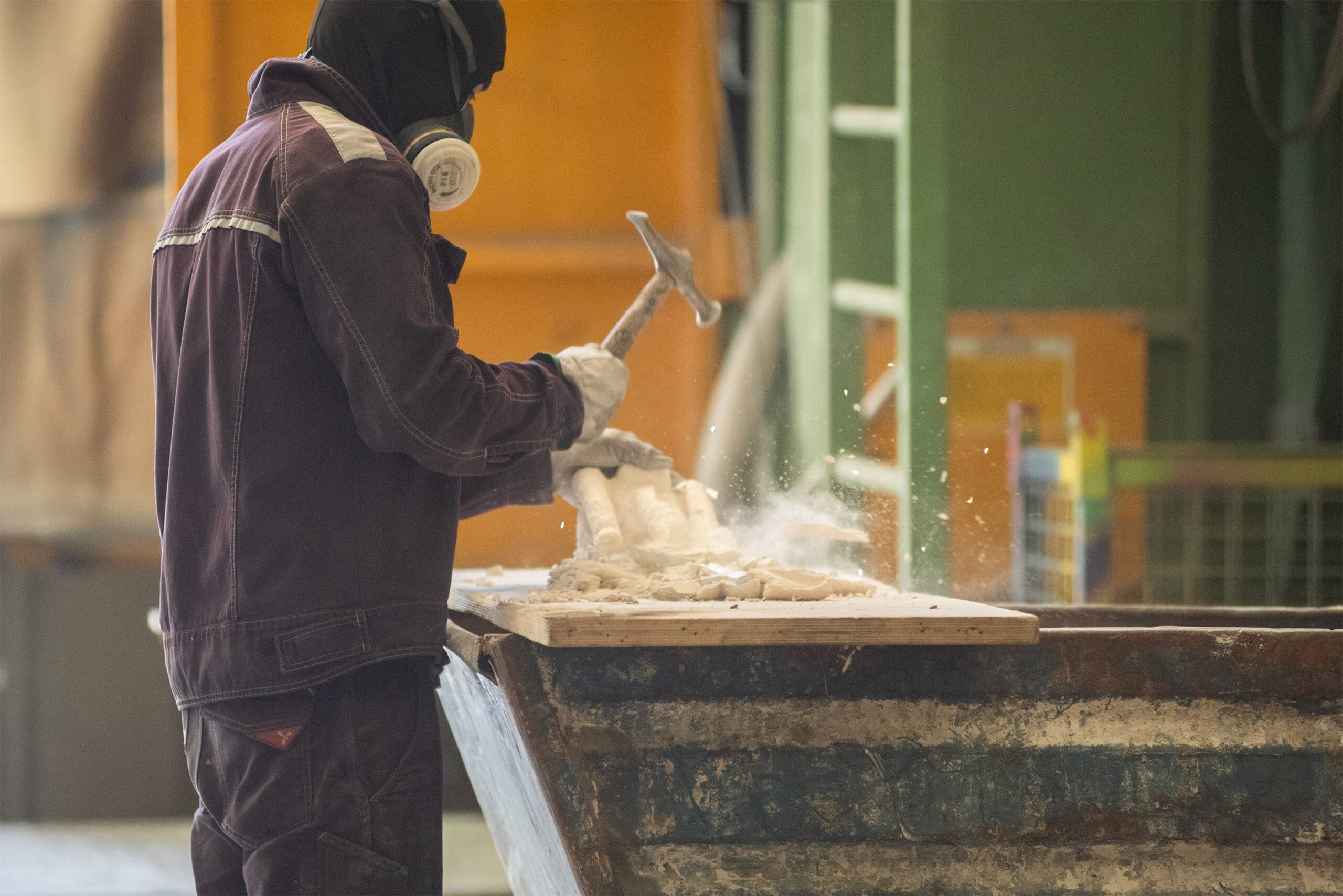 Operator removing the ceramic treatment from a mold in the sculpture casting process at Capa Esculturas.