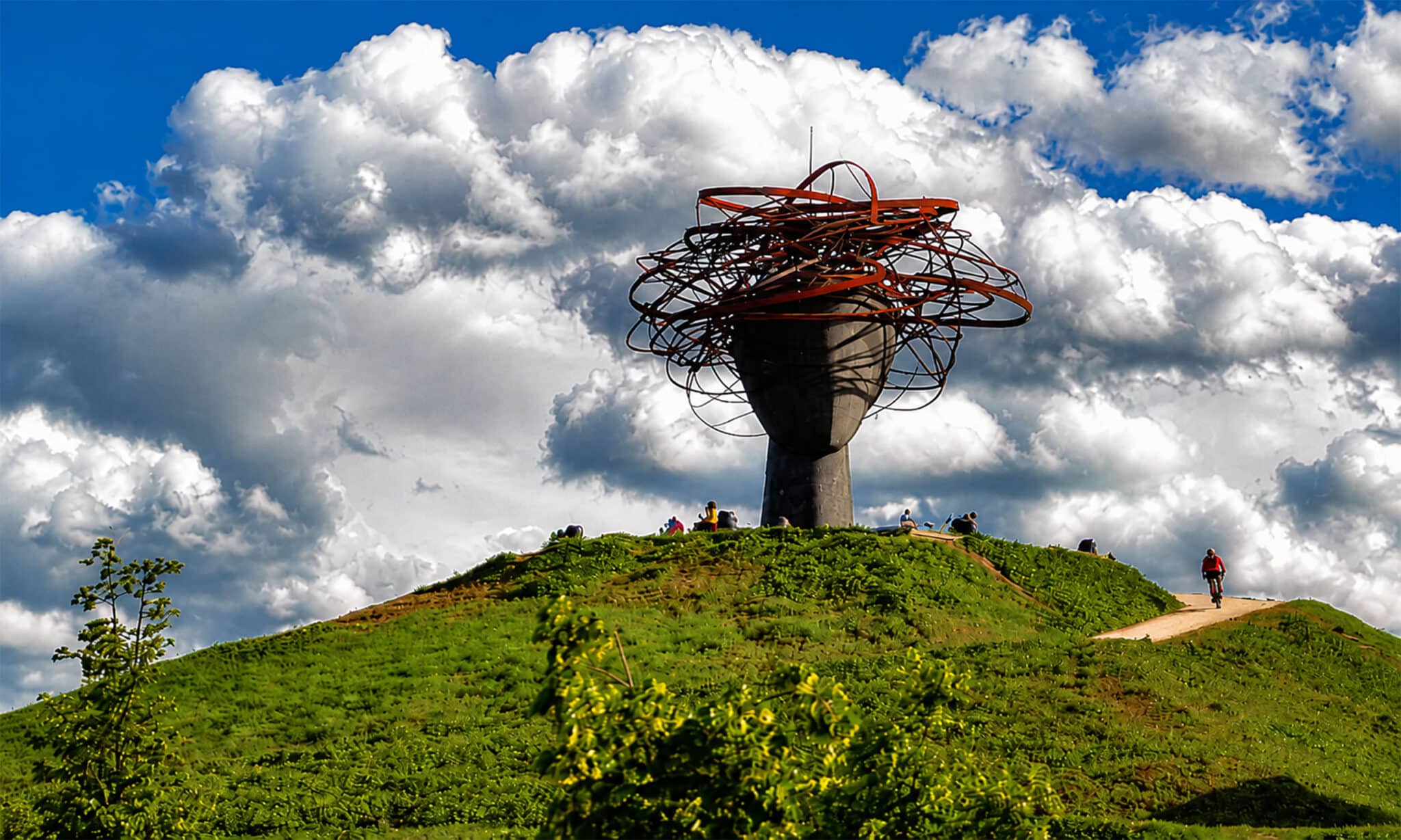 Escultura contemporánea monumental instalada sobre una colina e integrada en un espacio público y natural.