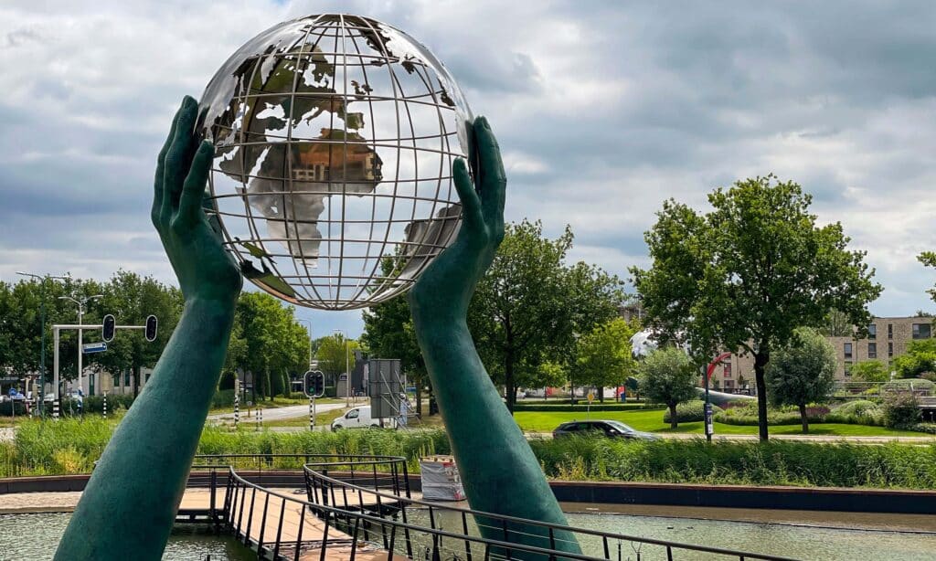 Detalle del globo metálico de la escultura “Your World”, sostenido por manos gigantes en su instalación final en Holanda.