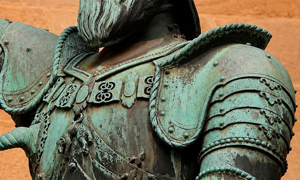 Detalle de una escultura de bronce con oxidación y pátina verde natural sobre la superficie metálica.
