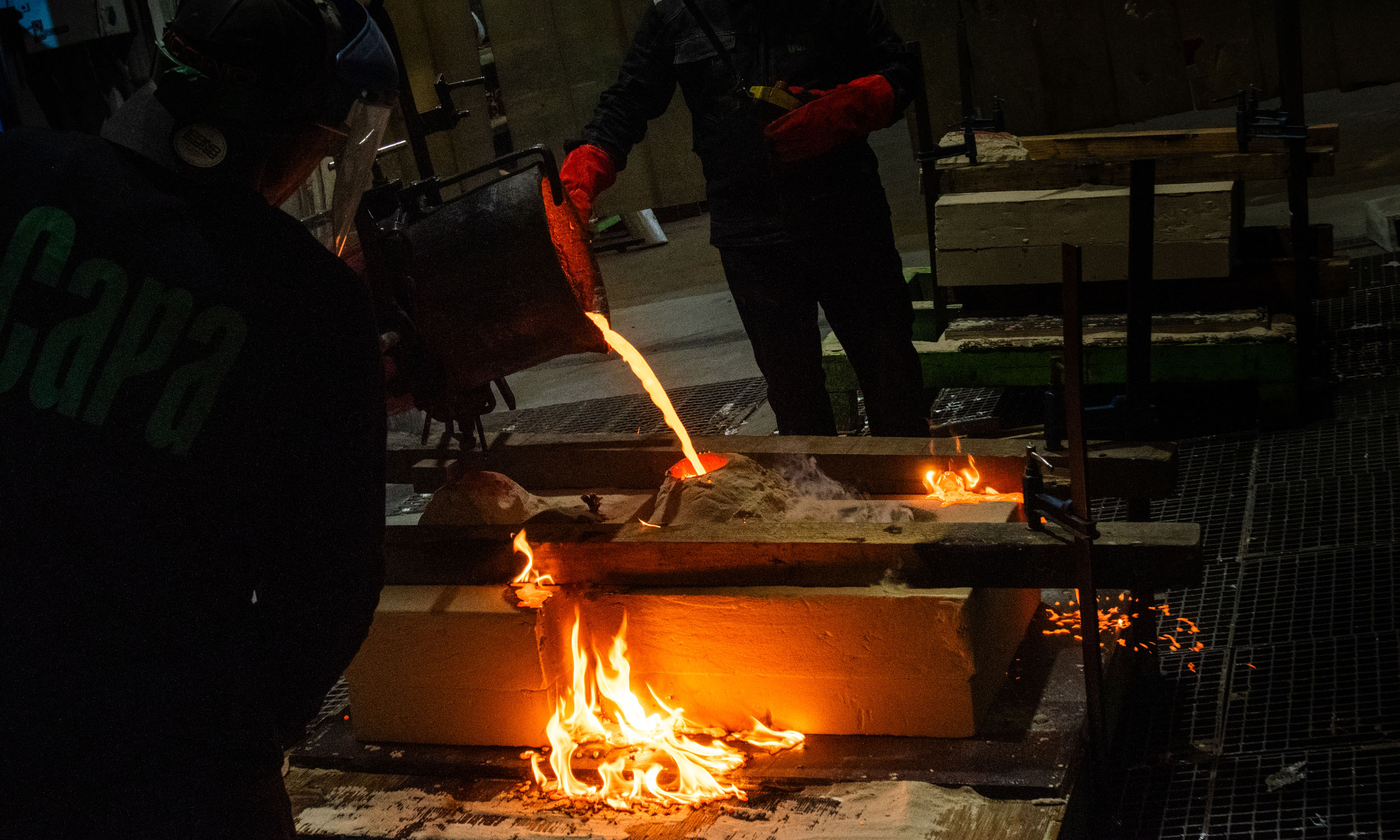 Proceso de fundición de esculturas de bronce en Capa Esculturas, con colada de metal fundido dentro de un taller de fundición artística.