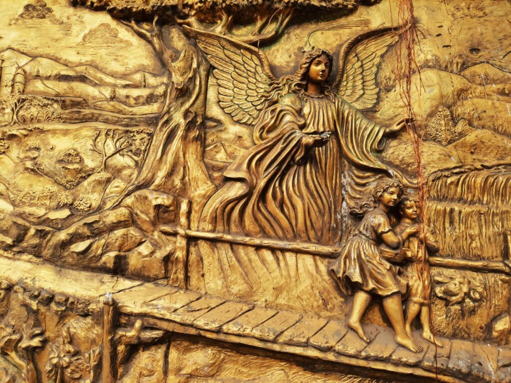Relieve dorado con un ángel protegiendo a dos niños, ejemplo de arte religioso en escultura en relieve.